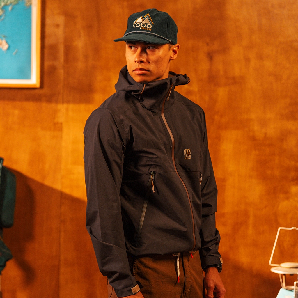 Person wearing a Corduroy Trucker Hat with a logo against an orange wall