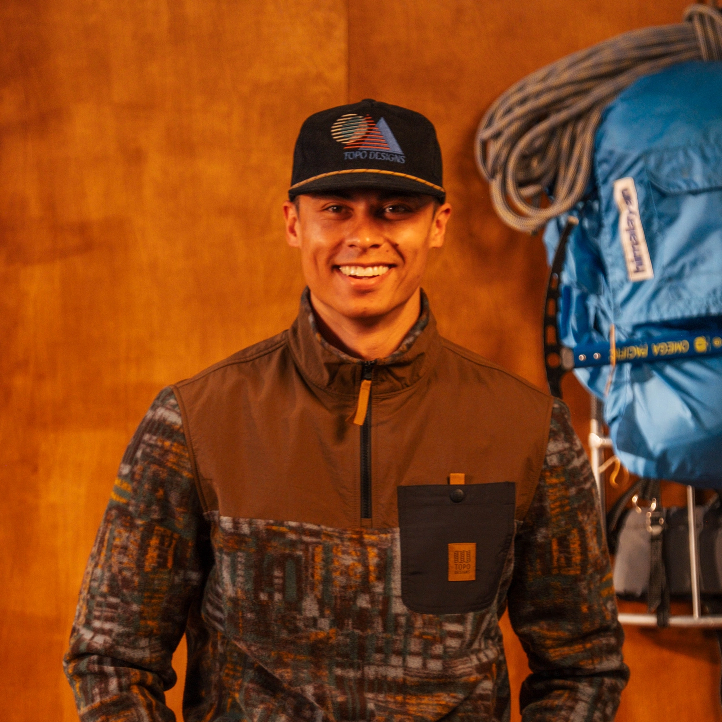 Person wearing a Corduroy Trucker Hat with a logo against an orange wall