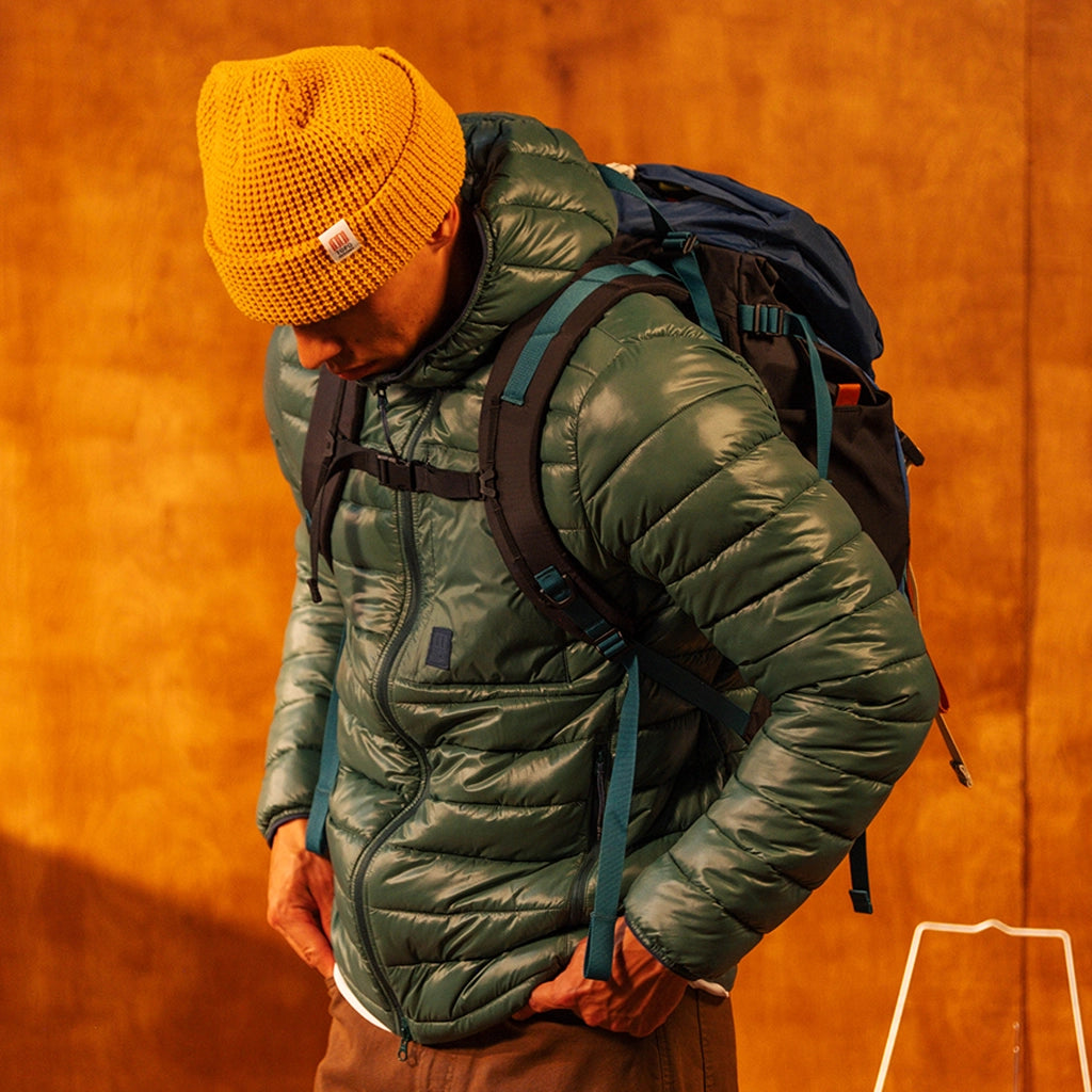 General image of person wearing a yellow waffle knit beanie standing against a white wall.