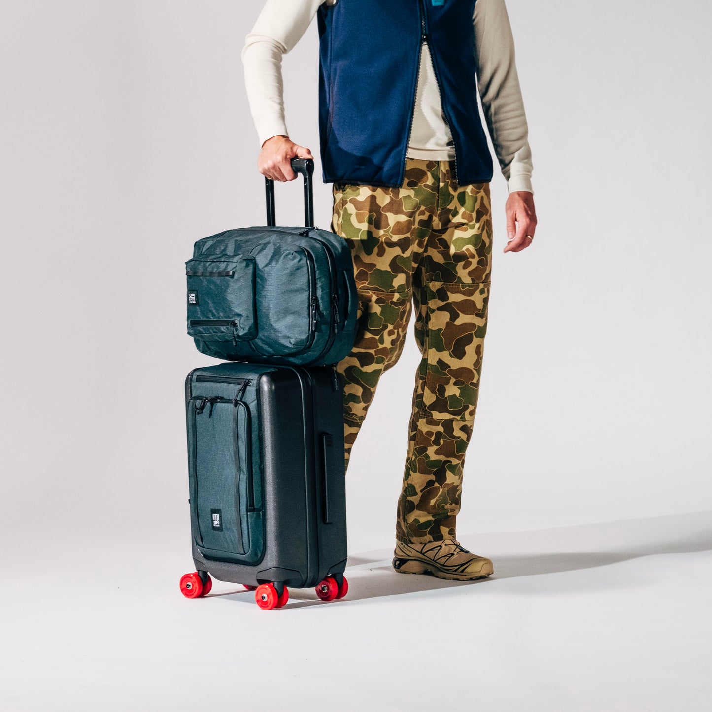 General shot of Topo Designs Global Pro Backpack shown in studio setting with system compatible roller bag
