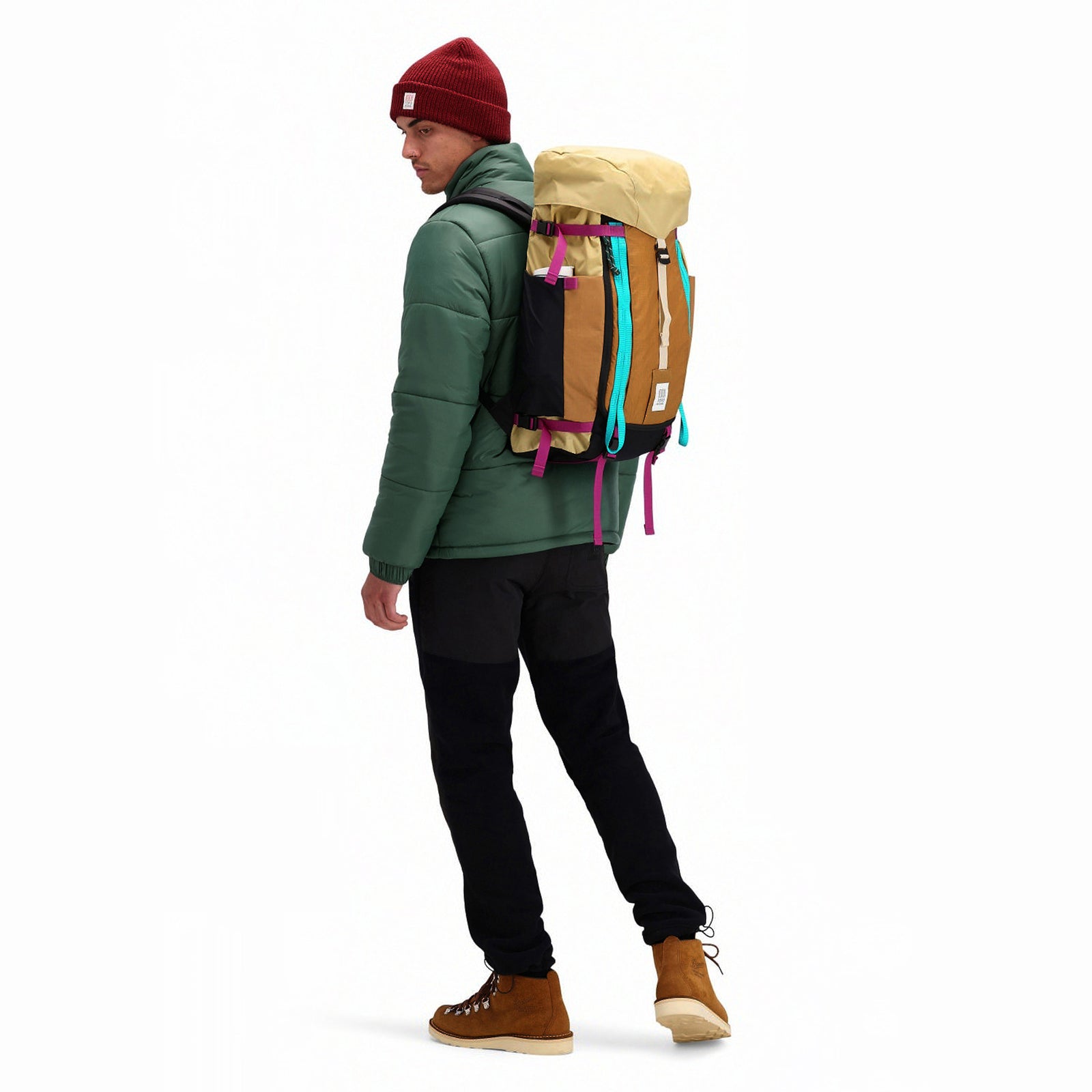 Model wearing Topo Designs Mountain Pack 28L hiking backpack with external laptop sleeve access in lightweight recycled "hemp / bone brown" nylon. 