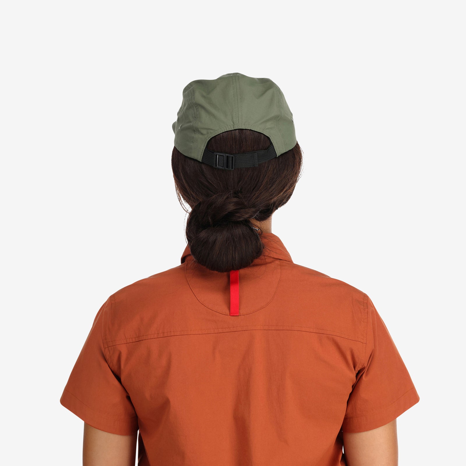 Back shot of model wearing Topo Designs Nylon Camp 5-panel flat brim Hat in "olive" green.