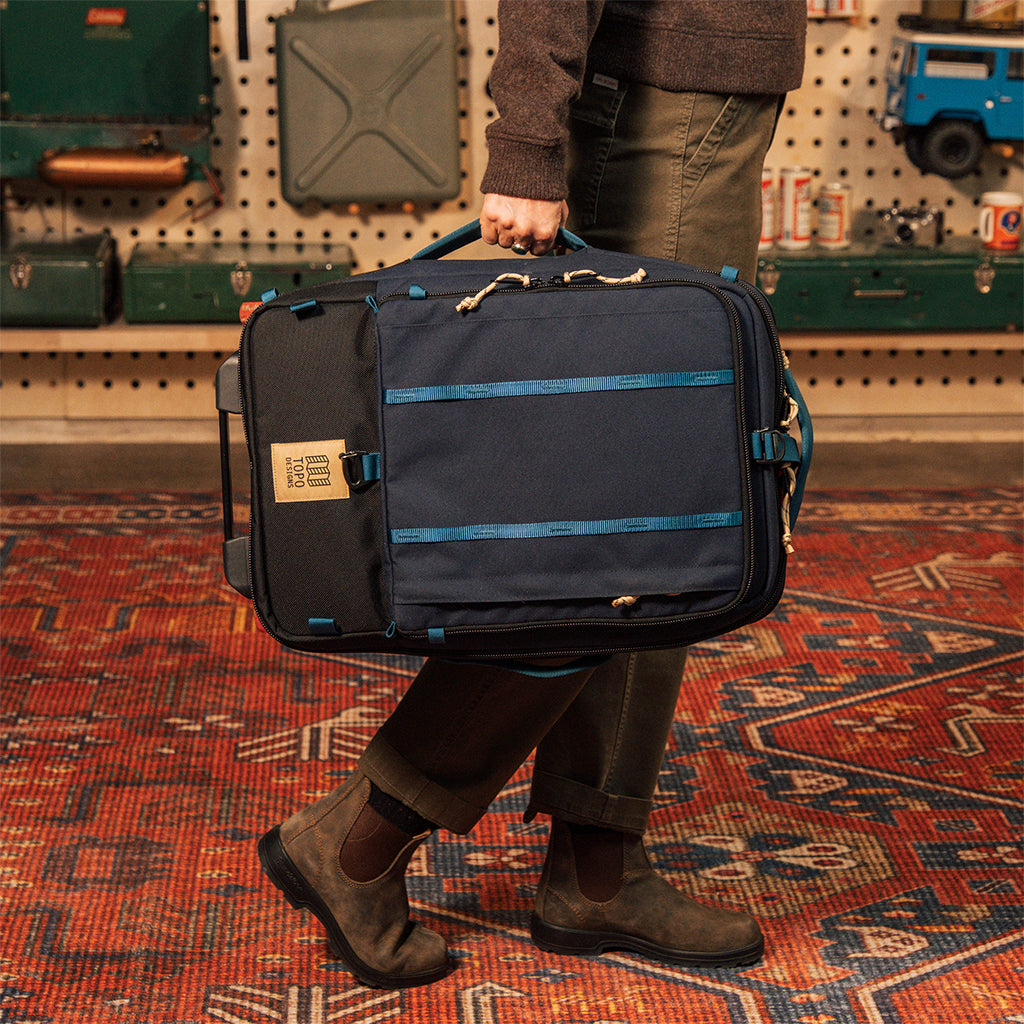 General model shot of Global Travel Roller Bag in "Navy" being carried by side handle