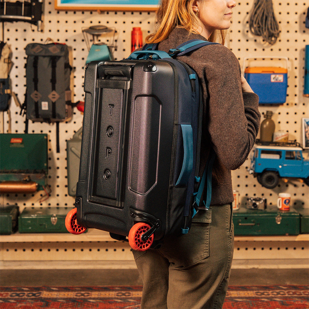 General model shot of Global Travel Roller Bag in "Navy" being worn on back with backpack straps