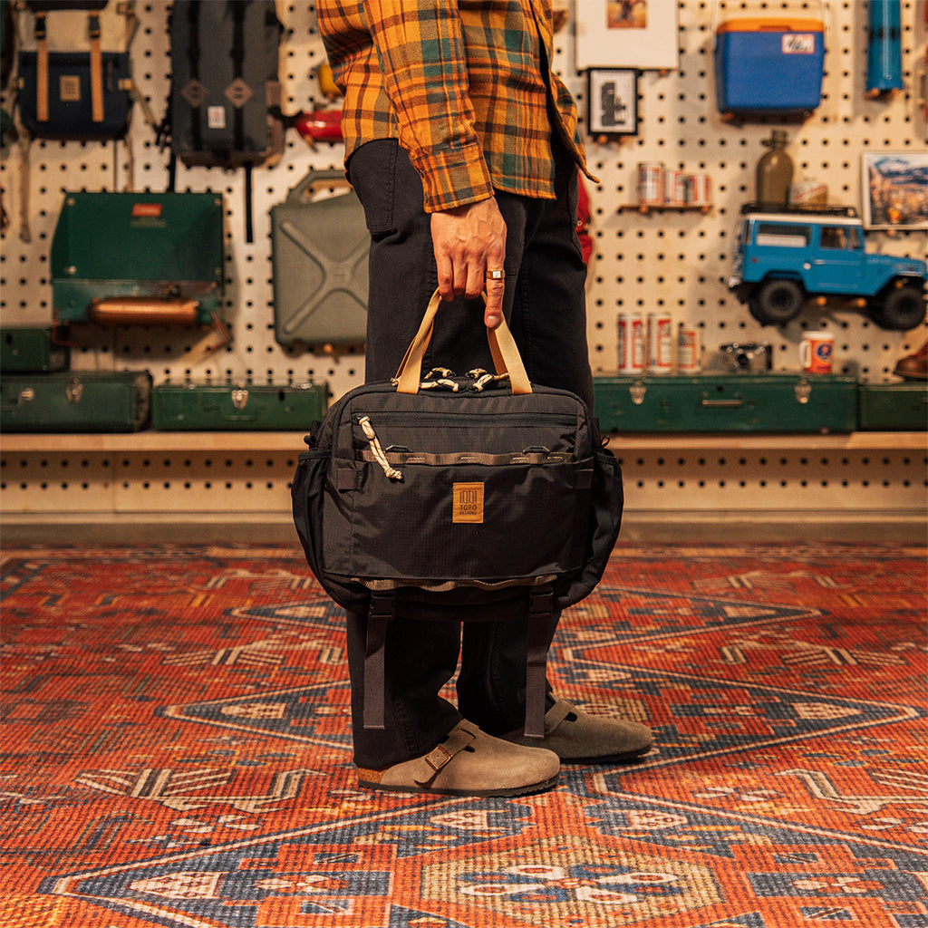 General on model shot of Mountain Cross Bag in "Black / Neutral" being carried by carry handles