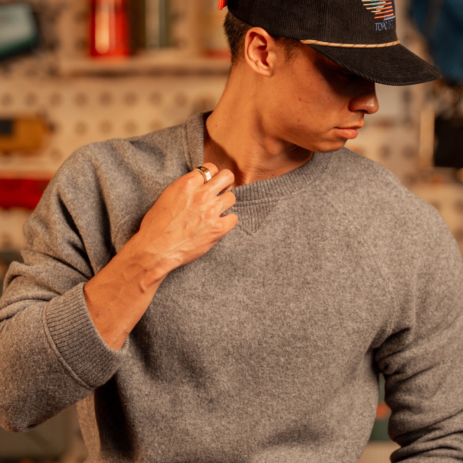 Person wearing a gray sweater and black cap in an indoor setting