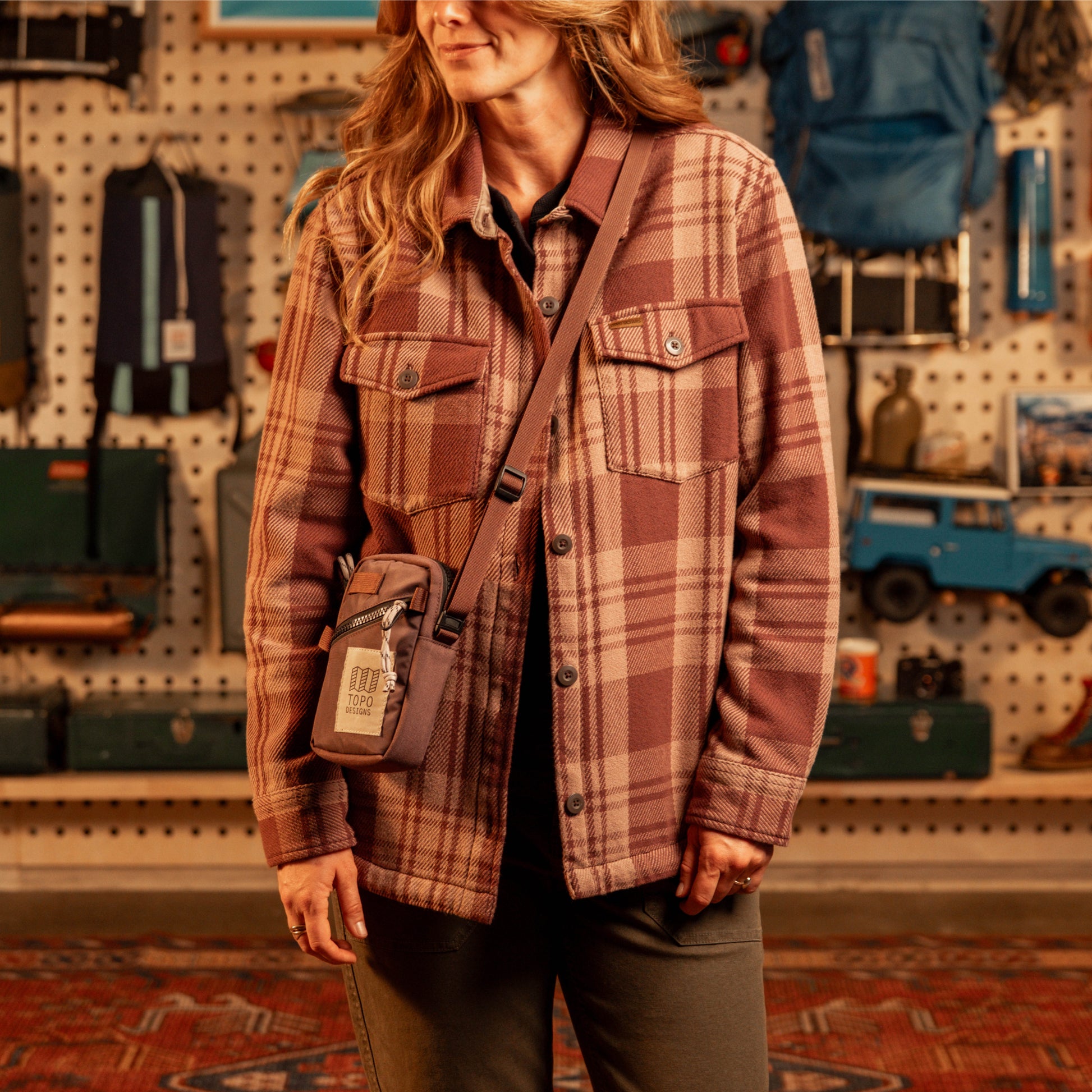 Person wearing a plaid shirt with a crossbody bag in a store setting