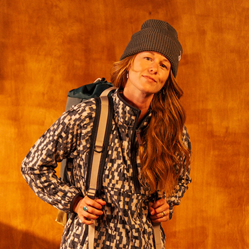 General image of person wearing a charcoal waffle knit beanie standing against a white wall.