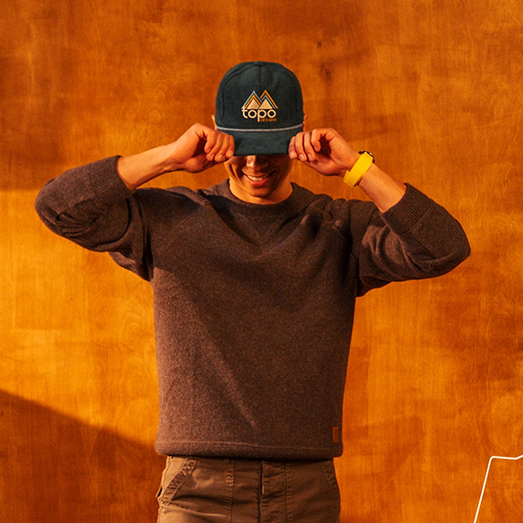 Person wearing a Corduroy Trucker Hat with a logo against an orange wall