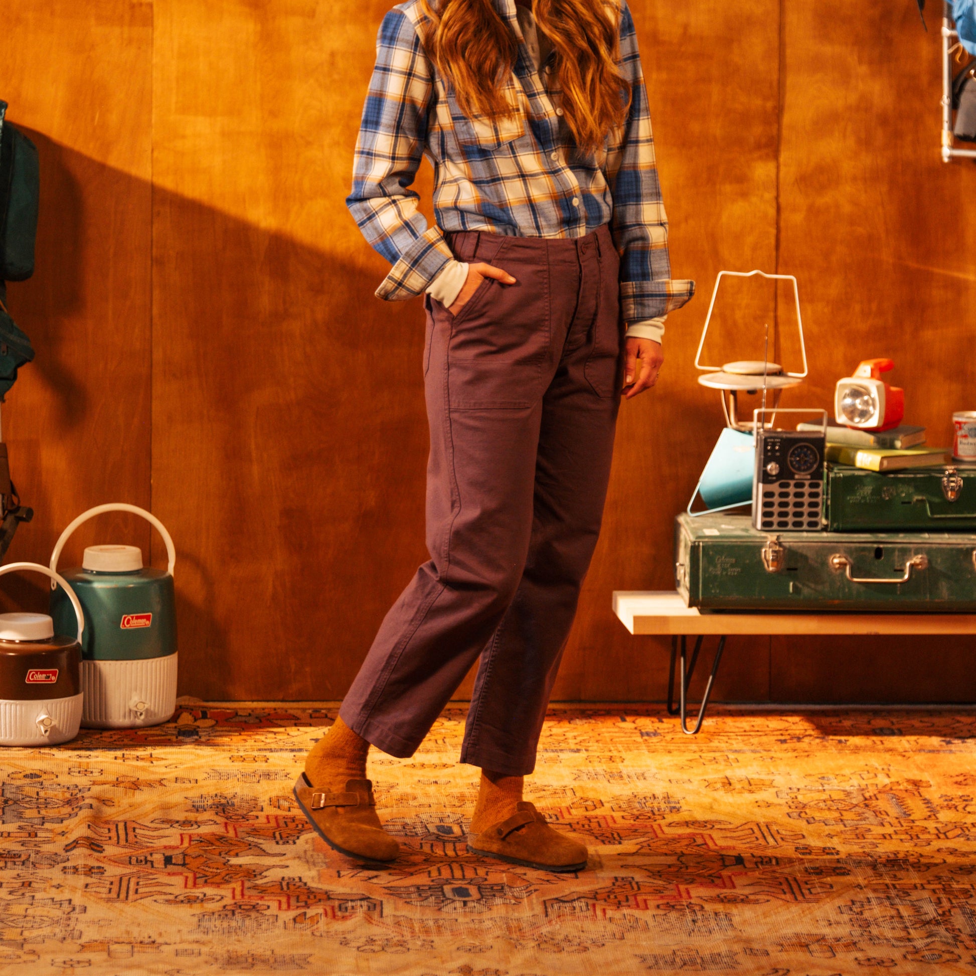 Person wearing a plaid shirt and purple pants standing in a room with vintage equipment.