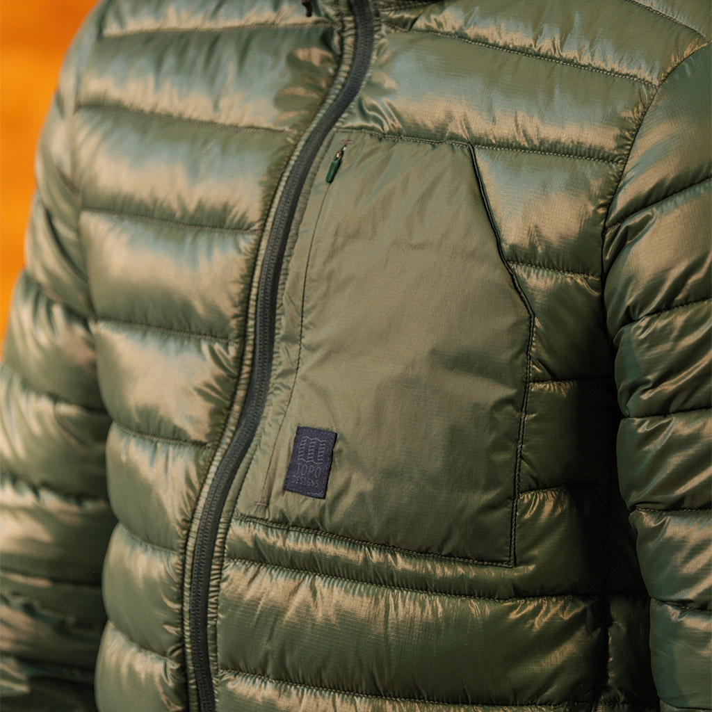 Green puffer jacket detail image showing the patch pocket styling