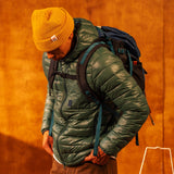 General image of person wearing a yellow waffle knit beanie standing against a white wall.