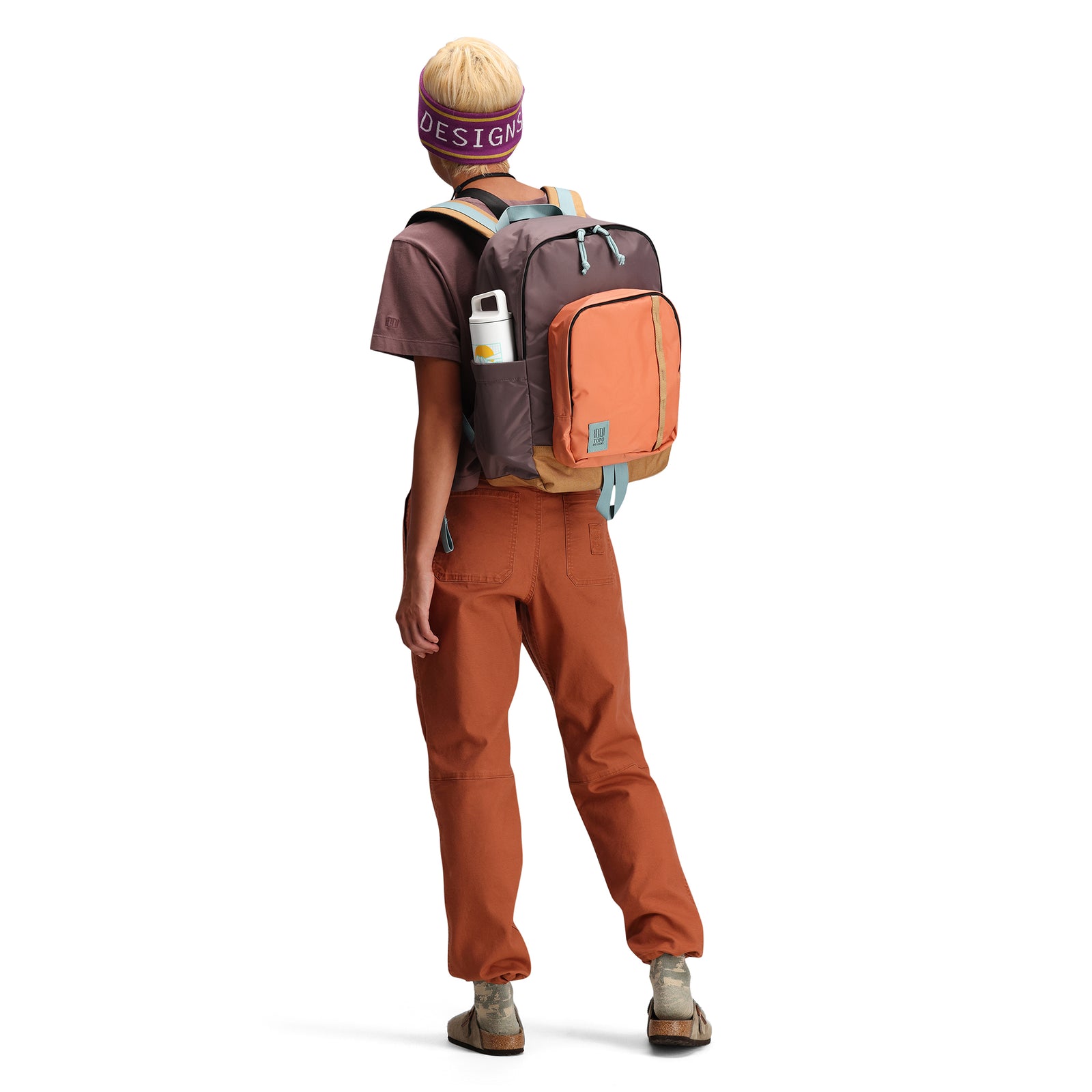 Angled back model shot of Topo Designs Session Pack laptop backpack in "Coral / Peppercorn"