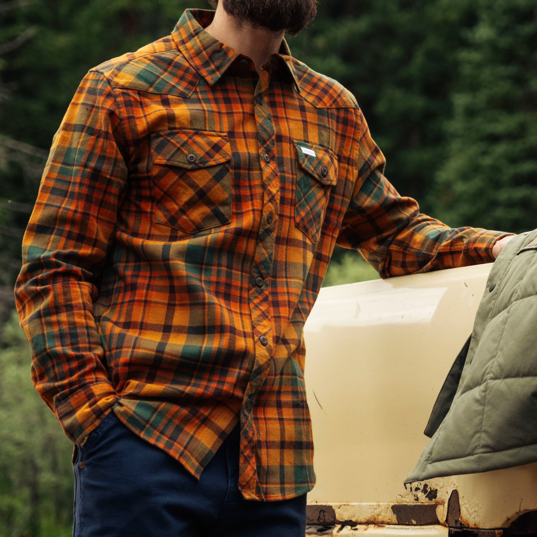 Person wearing a plaid shirt in a forest setting