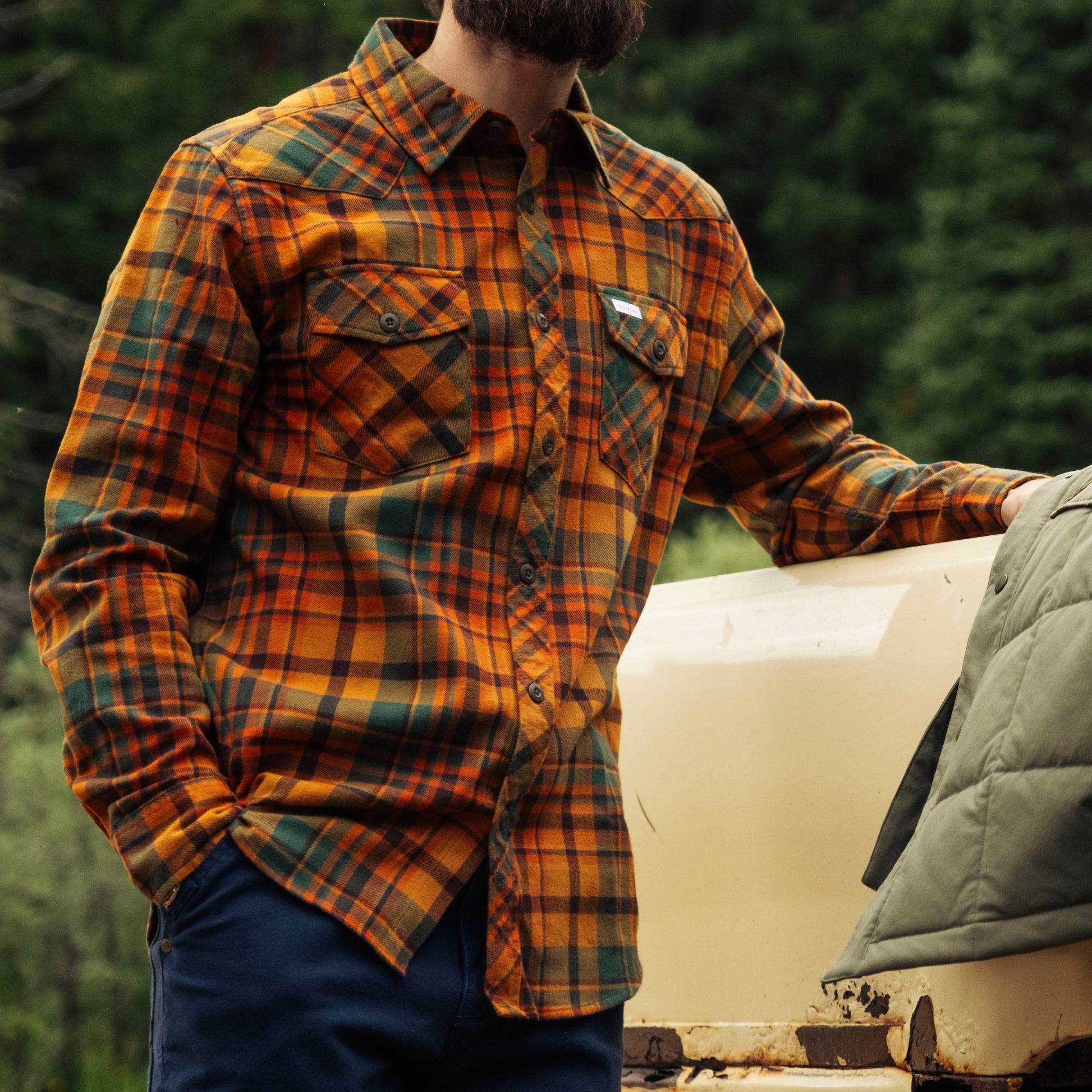 Person wearing a plaid shirt in a forest setting