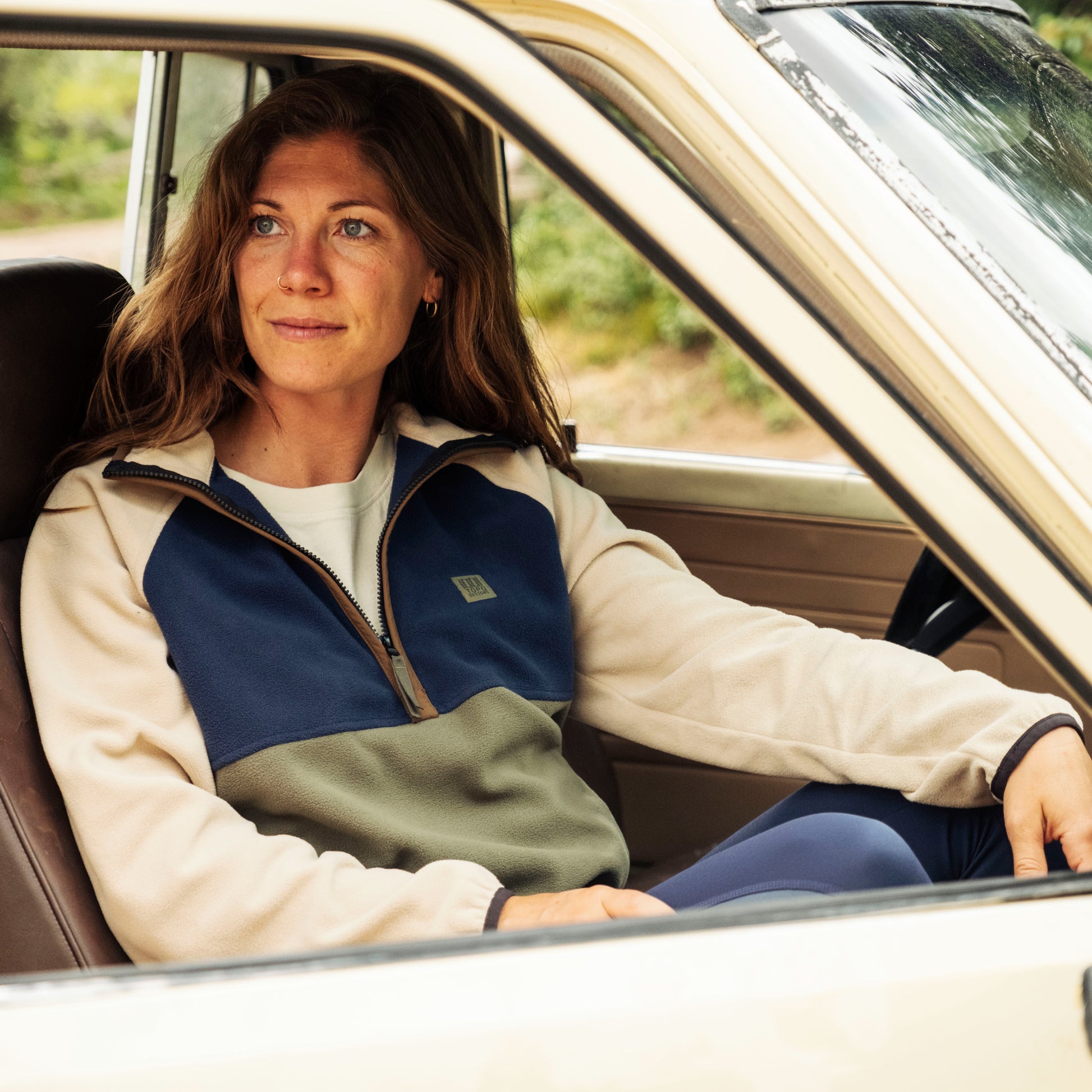 Woman sitting inside a car wearing a three-tone fleece jacket.