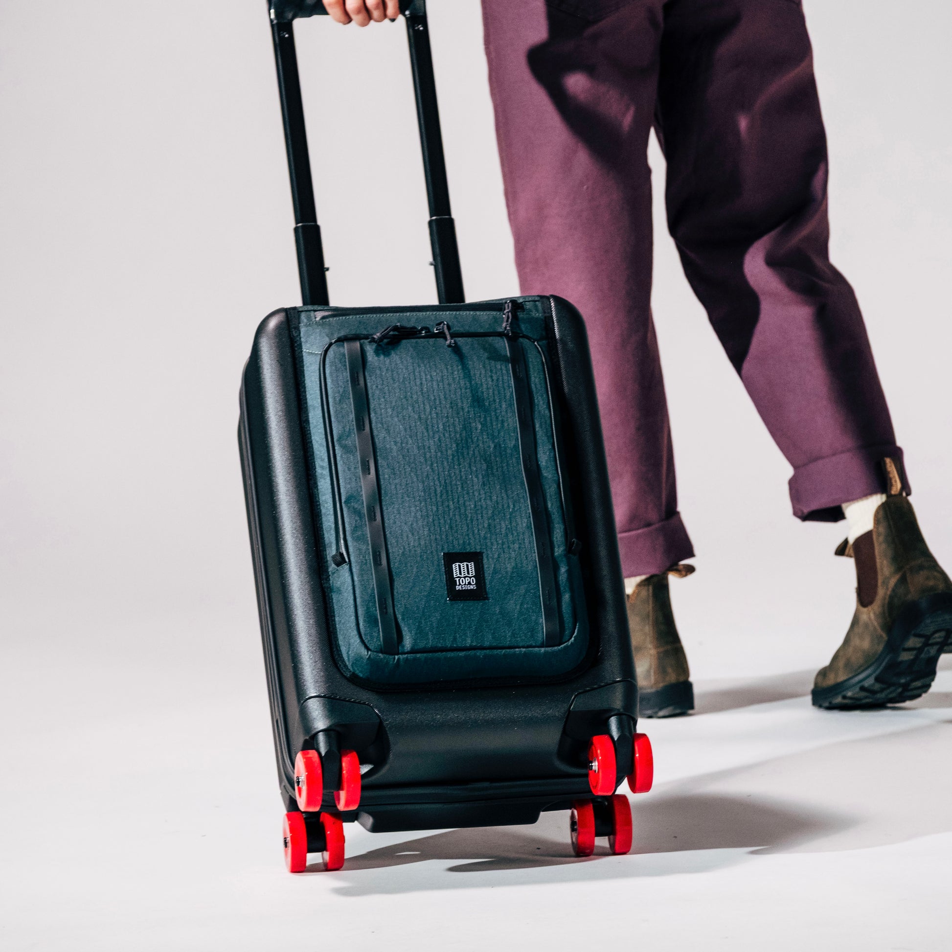 General shot of Topo Designs Global Pro Travel Roller in studio setting with wheels angled and rolling