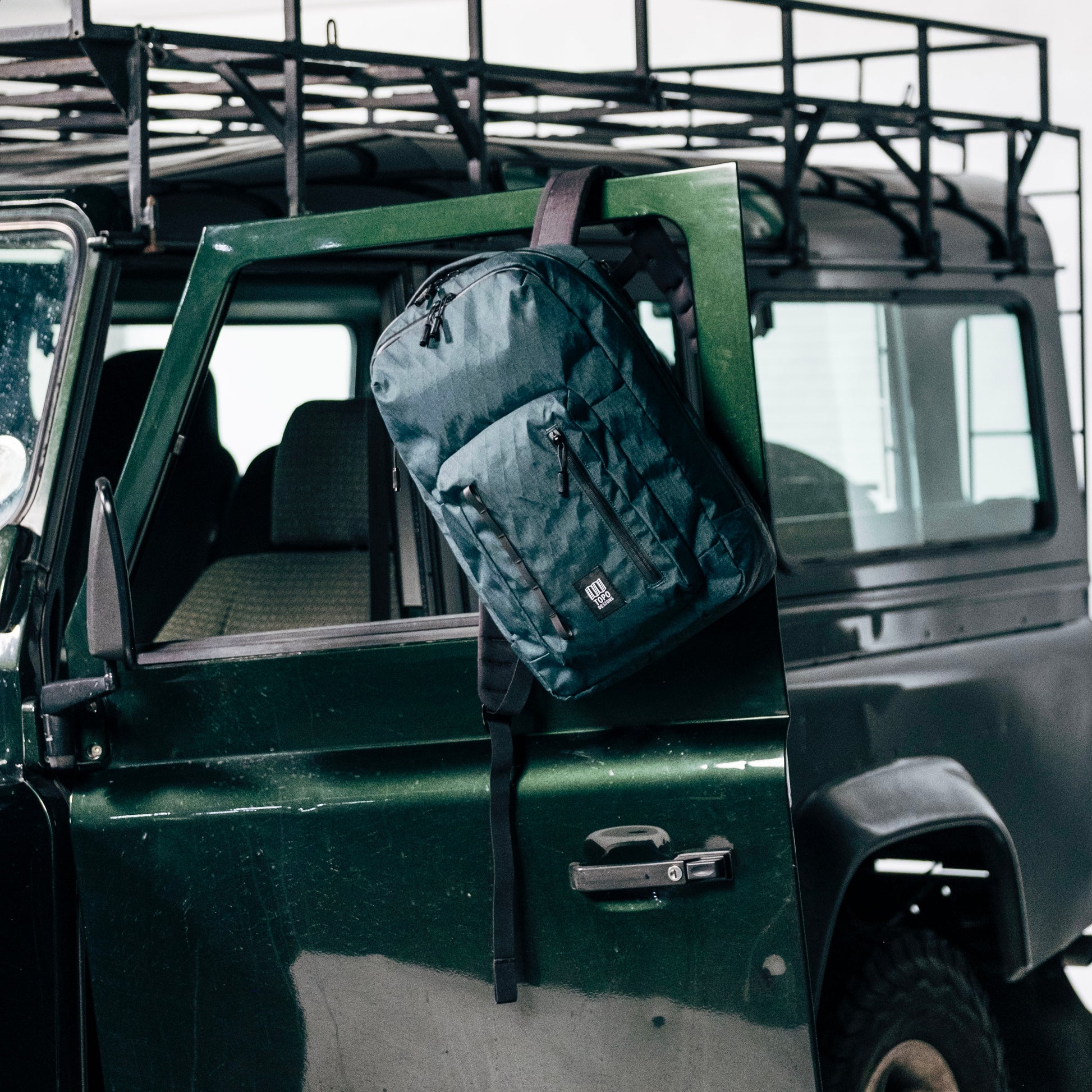 General shot of Topo Designs Global Pro Backpack shown in studio setting on green truck