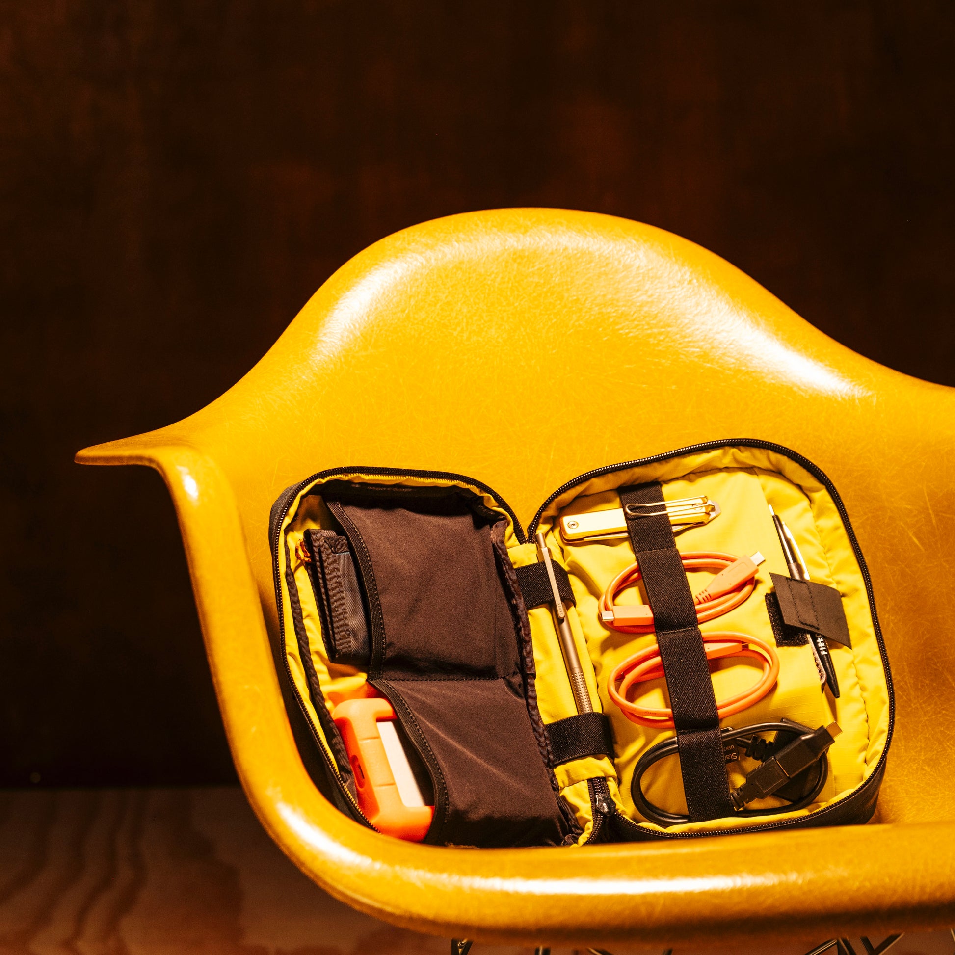 General shot of Topo Designs Tech Case in studio setting shown open with assortment of tech accessories