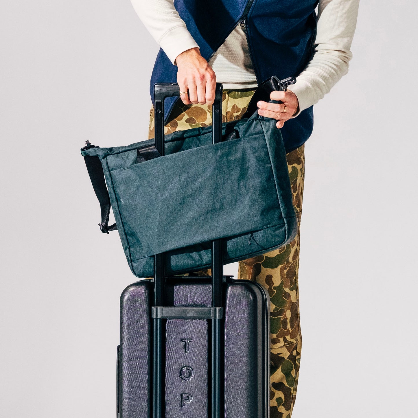 General lifestyle shot of Topo Designs Global Pro Travel Tote showing system compatibility with roller bag