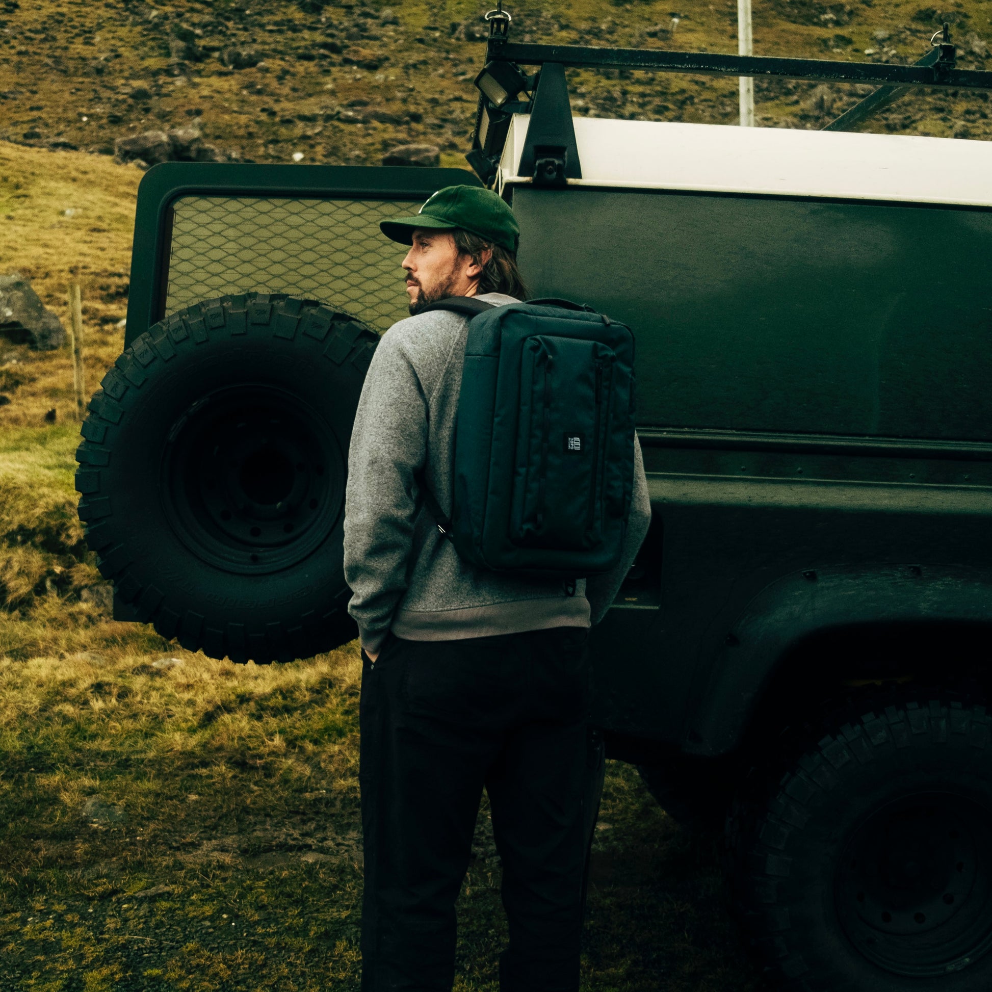 General lifestyle shot of Topo Designs Global Pro 3-Way Briefcase showing the bag worn by a man standing by a truck