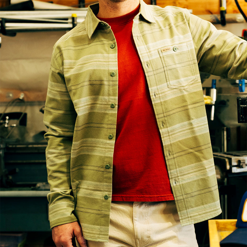 Person wearing an "Oil Green Horizontal Stripe" Mountain Shirt Lightweight over a red shirt in an indoor setting