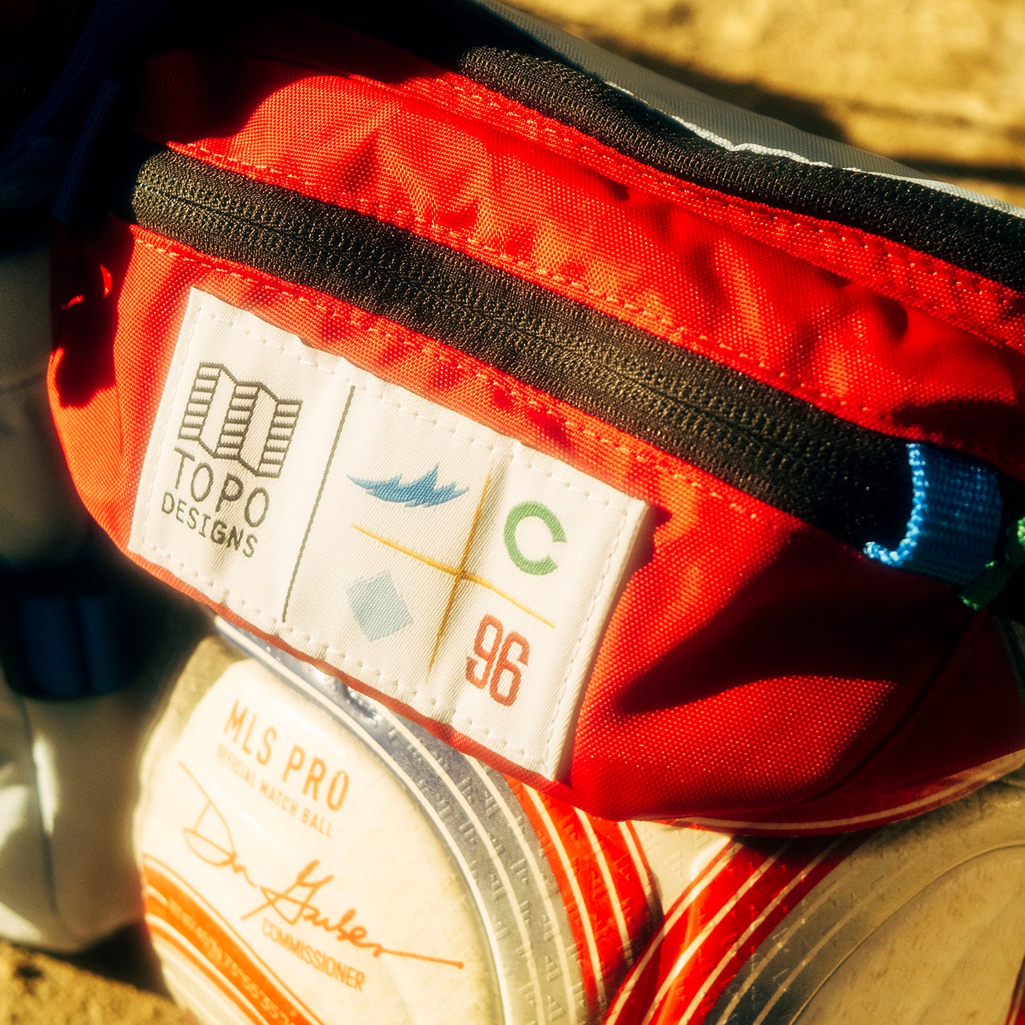 General lifestyle shot of Topo Designs x Colorado Rapids Mountain Waist Pack in "Rio Red / Glacier Blue"