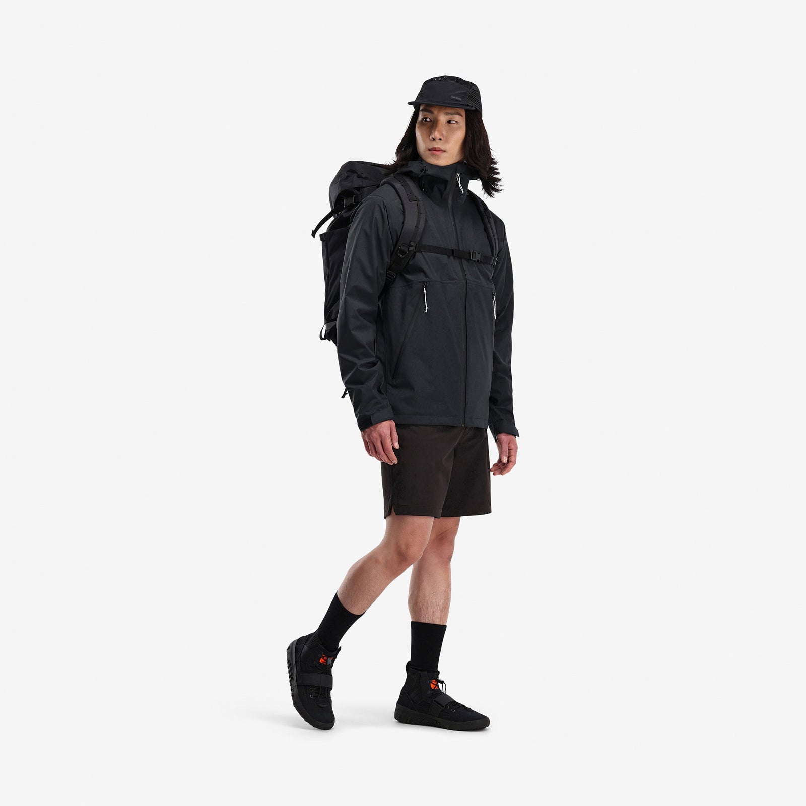 Model wearing Topo Designs Men's Global Jacket packable 10k waterproof rain shell in recycled "black" polyester.