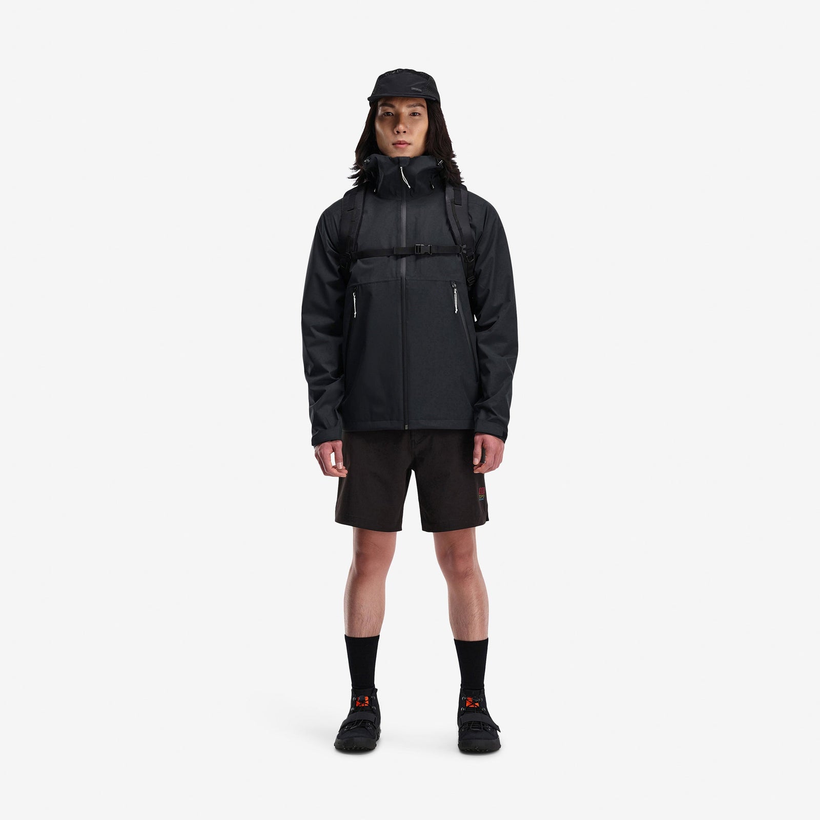 Model wearing Topo Designs Men's Global Jacket packable 10k waterproof rain shell in recycled "black" polyester.
