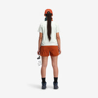 Back model shot of Topo Designs Women's Global lightweight quick dry travel Shorts in "Brick" orange.