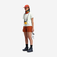 Side model shot of Topo Designs Women's Global lightweight quick dry travel Shorts in "Brick" orange.