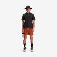 On model, front shot of Topo Designs Men's Global Shirt Short Sleeve 30+ UPF rated travel shirt in "Black".