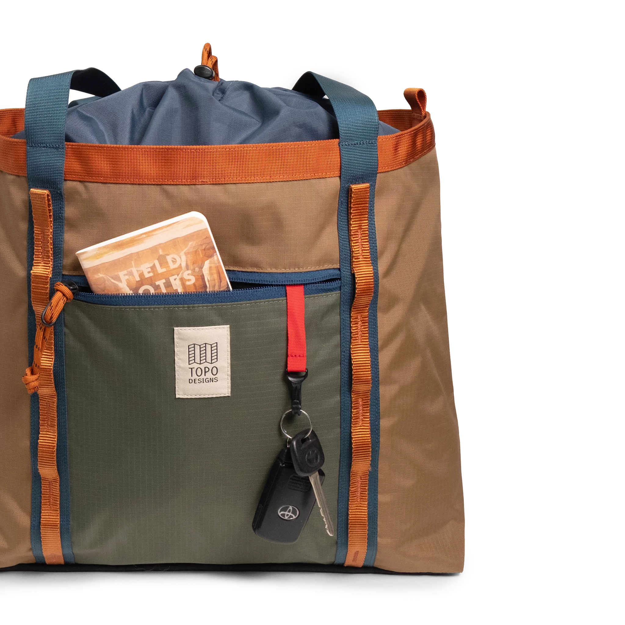 General front view of Topo Designs Mountain Utility Tote in "Olive / Dark Khaki" with notebook and keys.