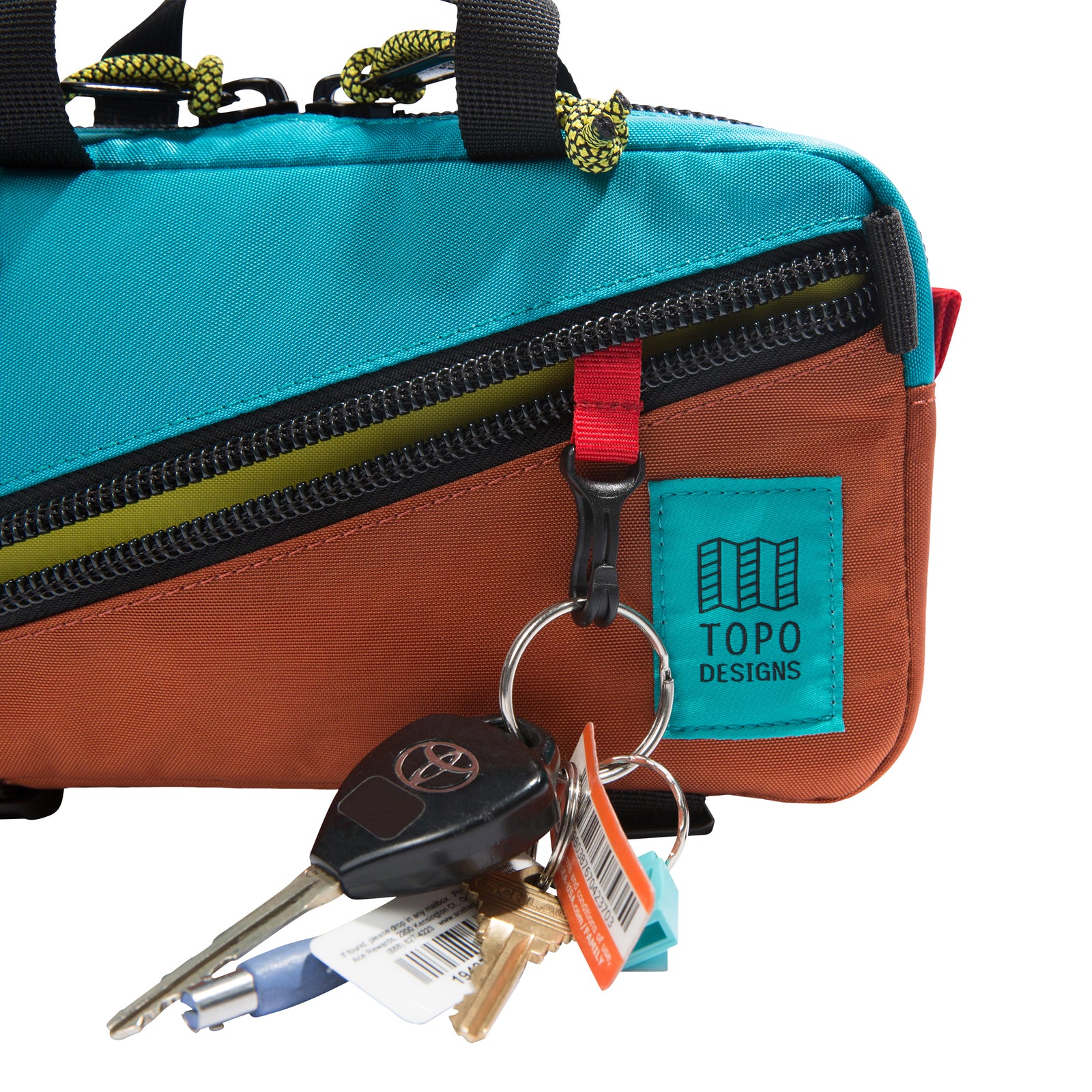 General detail shot of Topo Designs Mini Quick Pack in clay/turquoise showing external diagonal zippered pocket with internal key clip