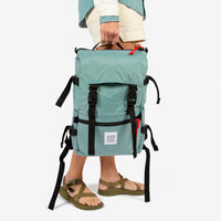 Topo Designs Rover Pack Classic in "Sage" green held by model with top carry handle.