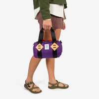 General shot of Topo Designs Mini Classic Duffel Bag shoulder crossbody purse in Purple held by model with top carry straps.