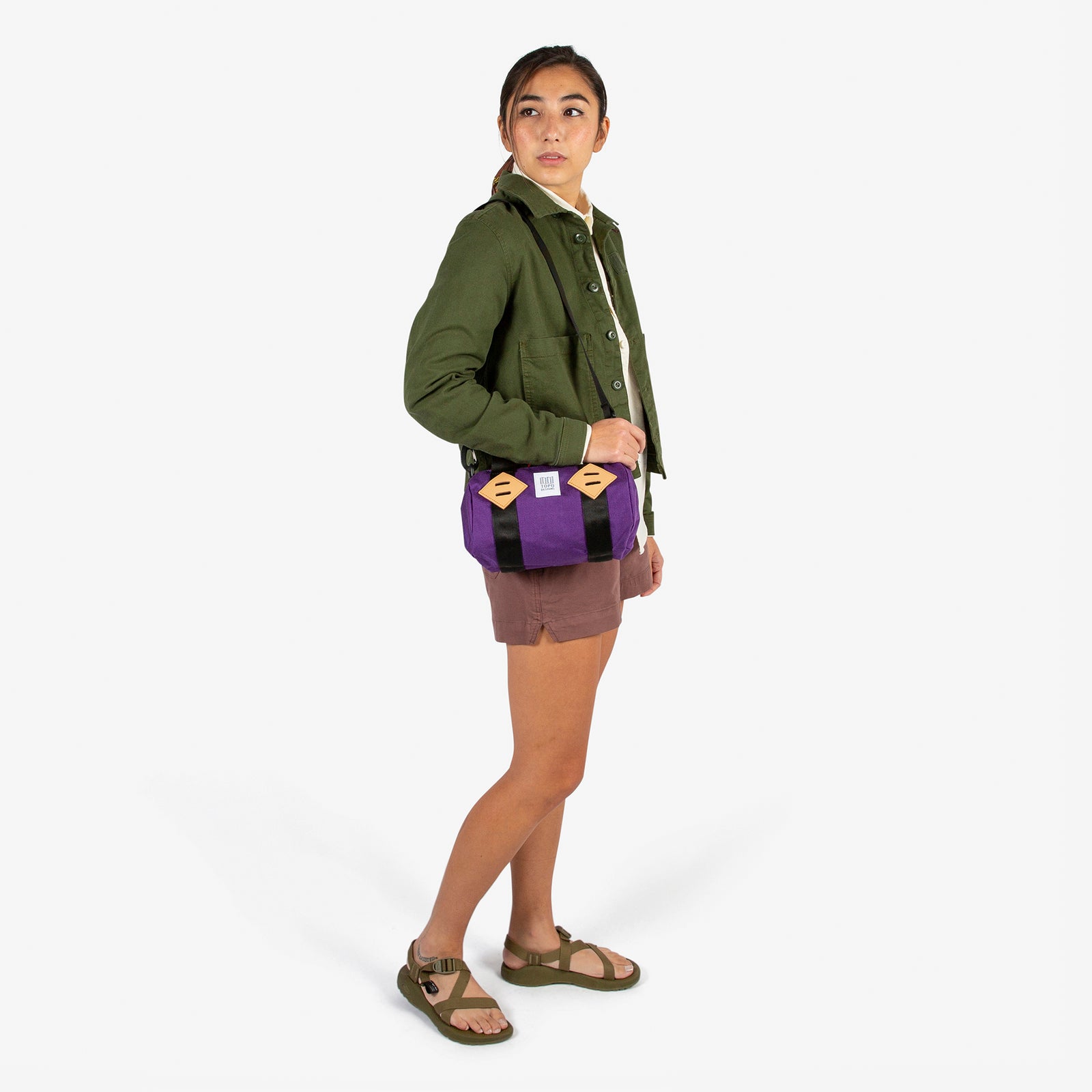 General shot of Topo Designs Mini Classic Duffel Bag shoulder crossbody purse in Purple held by model with shoulder strap.