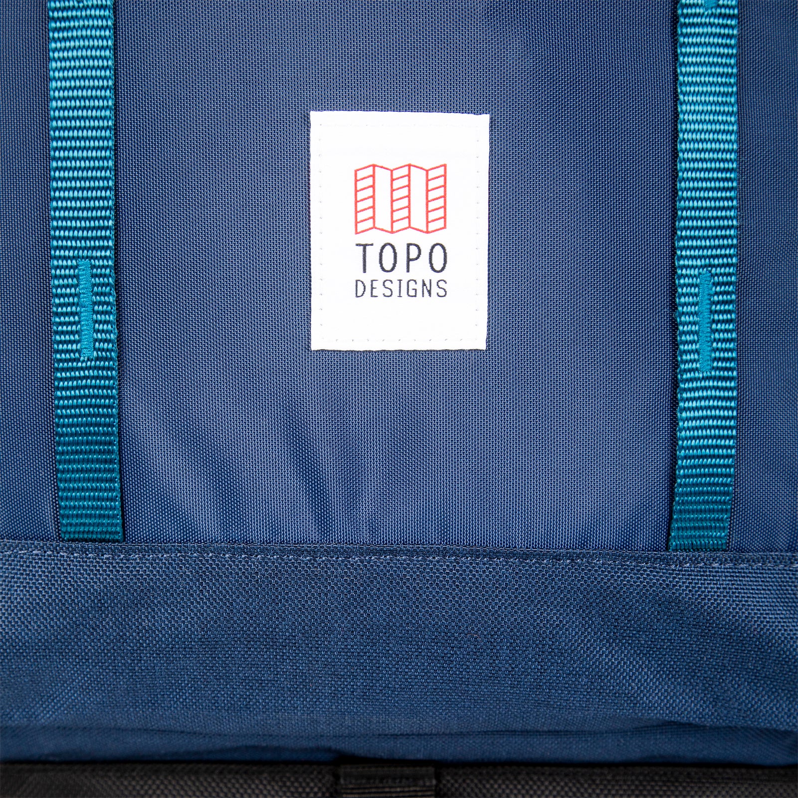 General shot of Topo Designs logo patch and front daisy chain webbing on Global Travel Bag 40L Durable Carry On Convertible Laptop Travel Backpack in Navy blue.