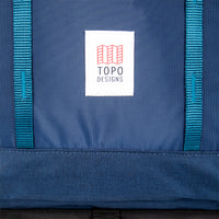 General shot of Topo Designs logo patch and front daisy chain webbing on Global Travel Bag 40L Durable Carry On Convertible Laptop Travel Backpack in Navy blue.