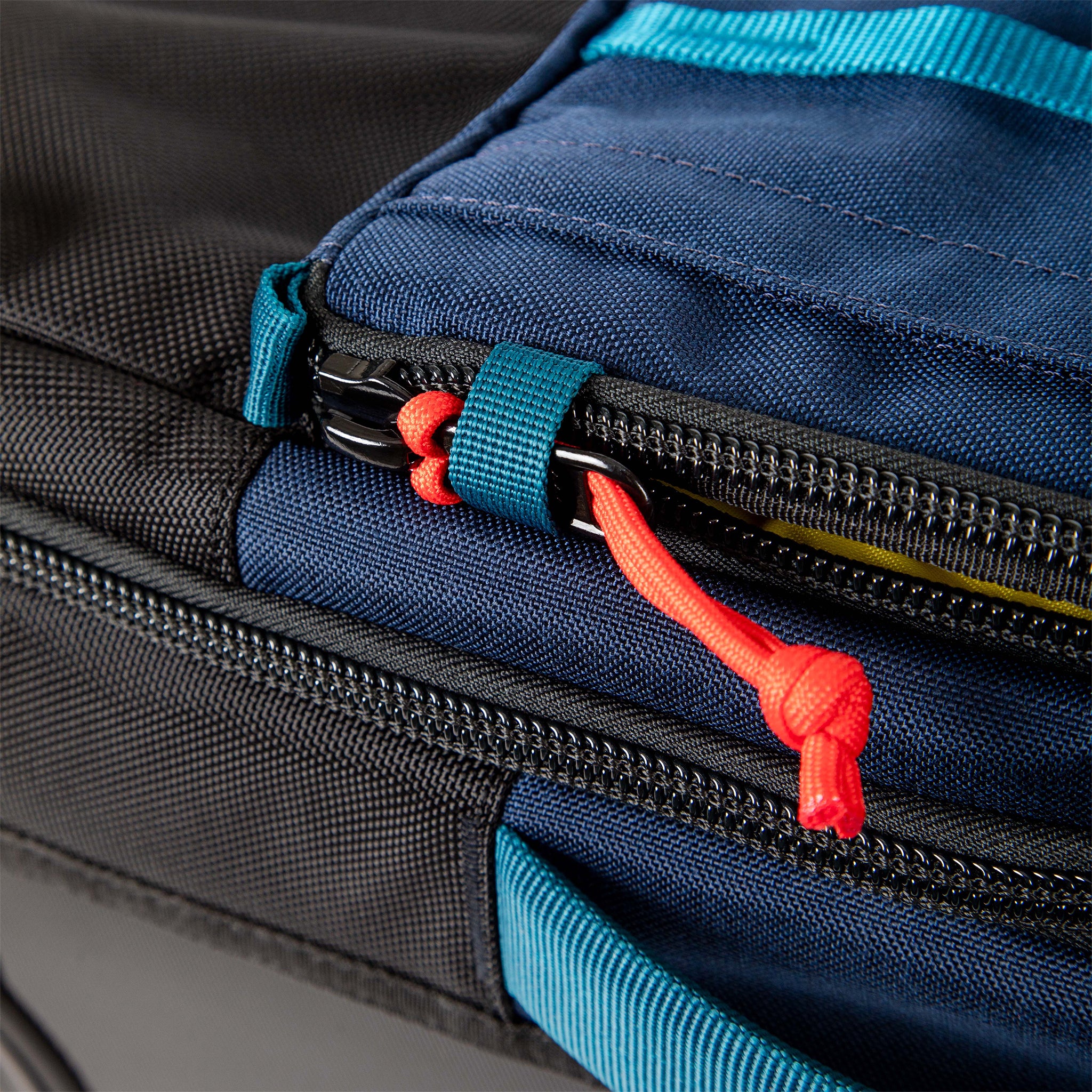 General shot of security zipper loops on Topo Designs Global Travel Bag Roller durable carry-on convertible laptop rolling backpack suitcase in Navy blue.