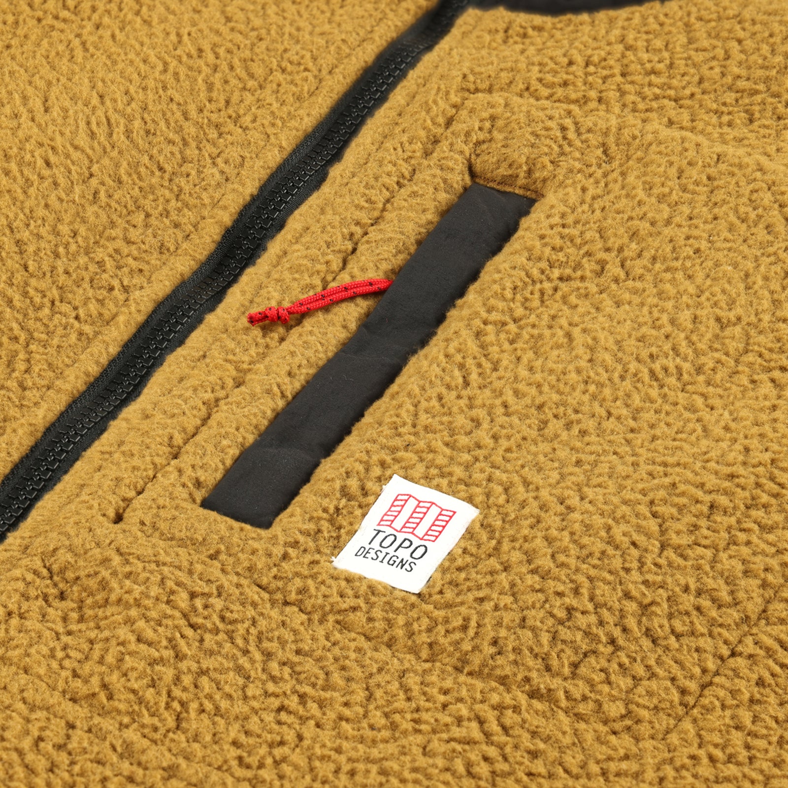 Detail shot of Topo Designs Men's Mountain Fleece Pullover in "dark khaki" brown showing chest zipper pocket and logo patch.