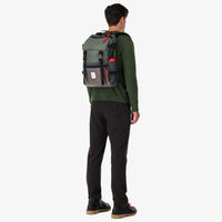 General shot of Topo Designs Rover Pack Heritage Made in the USA Backpack in Charcoal gray Leather on model's back with water bottle in sleeve.