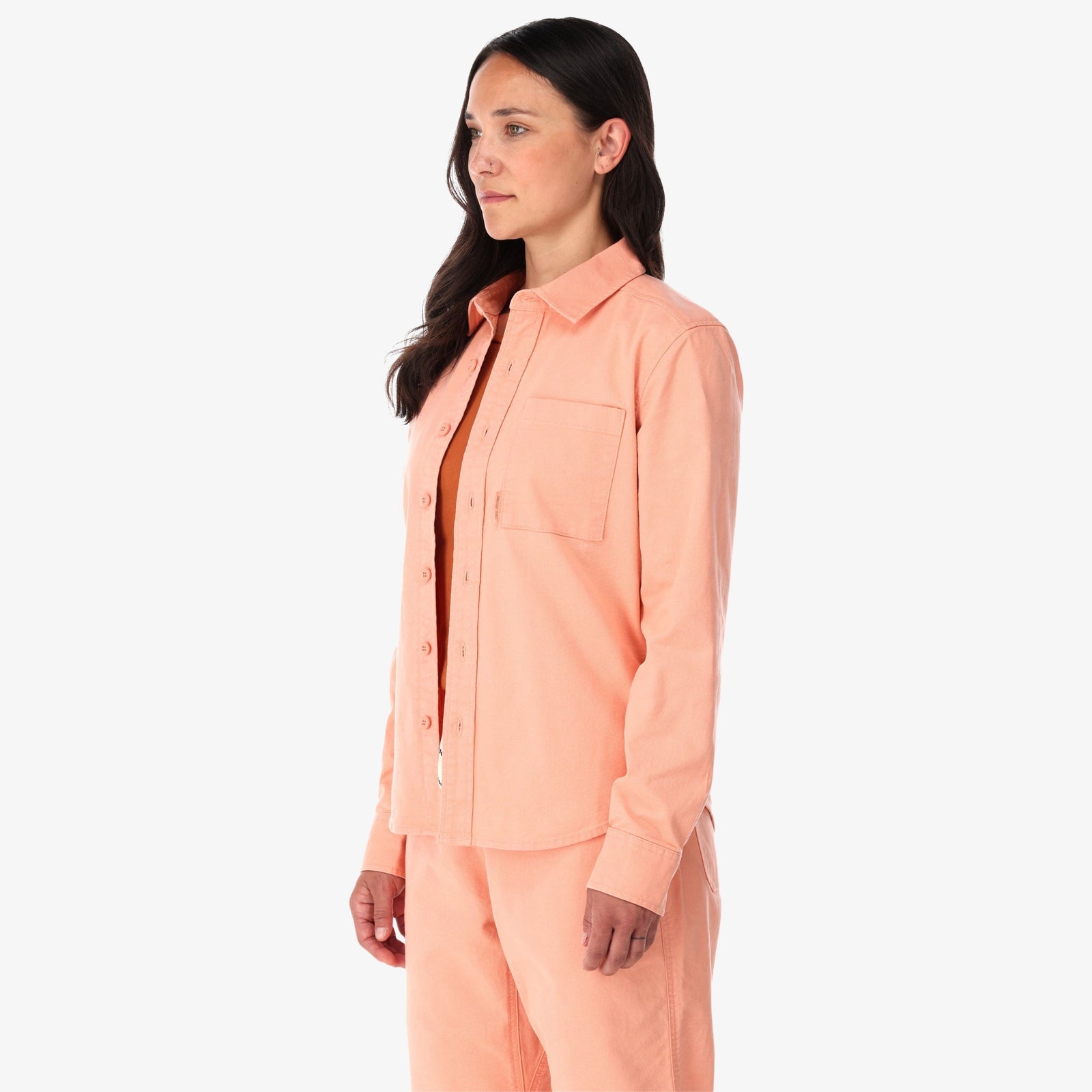 Topo Designs Women's Dirt Shirt long sleeve stretch cotton button-up in "peach" pink on model side.