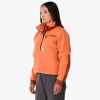 Side shot of Topo Designs Women's Mountain Fleece Pullover in "Rust / brick" pink orange on model.