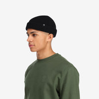 Side model shot of Topo Designs Global Beanie merino wool blend watchman cap in "black"