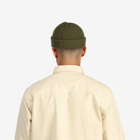 Back model shot of Topo Designs Global Beanie merino wool blend watchman cap in "olive" green.