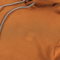 Detail shot of embroidered  chest logo on Topo Designs Men's Dirt Hoodie 100% organic cotton French terry sweatshirt in "Earth" brown. Show on "Pond Blue".
