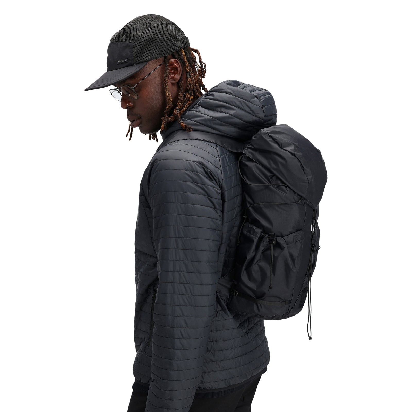 Model wearing Topo Designs Men's Global Puffer packable recycled insulated Hoodie jacket in "black"