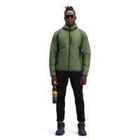 Model wearing Topo Designs Men's Global Puffer packable recycled insulated Hoodie jacket in "olive" green.