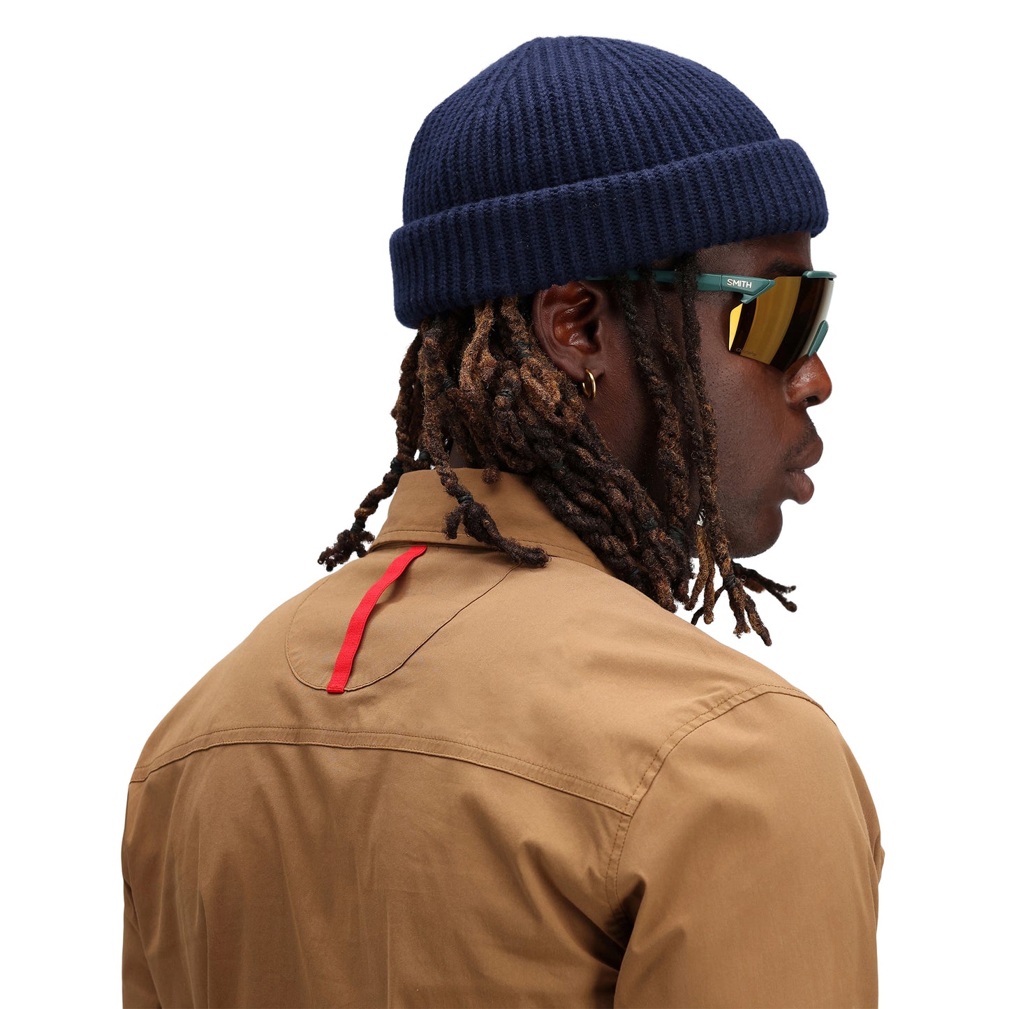 Model wearing Topo Designs Global Beanie merino wool blend watchman cap in "navy" blue.